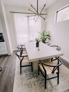 a dining room table with chairs and a chandelier hanging from the ceiling over it