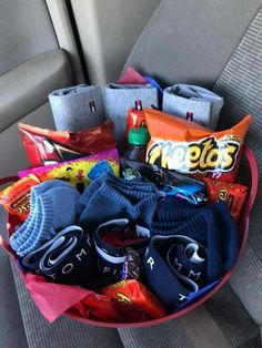 a car seat filled with lots of items in the passenger's side area, including t - shirts and socks