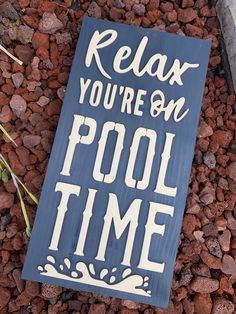 a blue sign that says relax you're on pool time next to some rocks