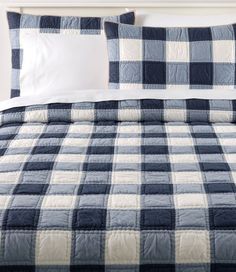 a blue and white checkered comforter set on a bed with two pillow cases