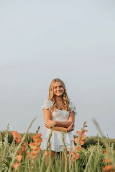 a woman standing in tall grass with her arms crossed