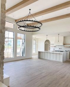 an empty kitchen and living room in a house with wood beams on the ceiling, large windows