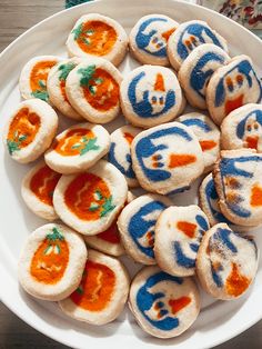 a white plate topped with cookies covered in frosting and painted orange and blue designs