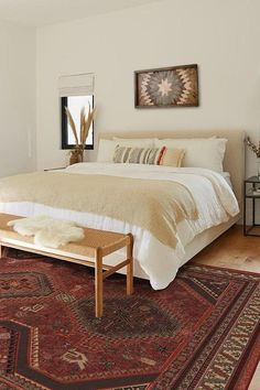 a large bed sitting on top of a wooden floor next to a red and white rug