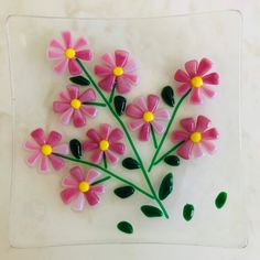 pink and yellow flowers are on a glass plate