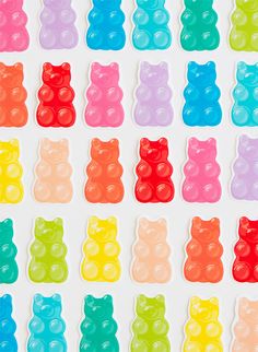 gummy bears are lined up in rows on a white surface with different colors and shapes