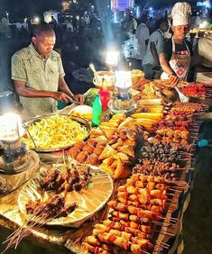 several people standing around a table filled with food