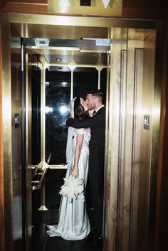 a bride and groom kissing in an elevator