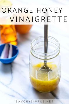 an orange honey vinaigrette is in a mason jar with a spoon inside