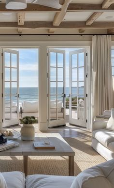 a living room filled with white furniture next to an open door leading to the ocean