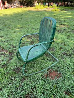 an old green lawn chair sitting in the grass