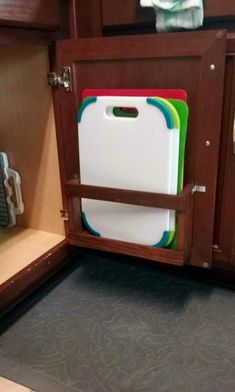 a kitchen cabinet with several cutting boards in it