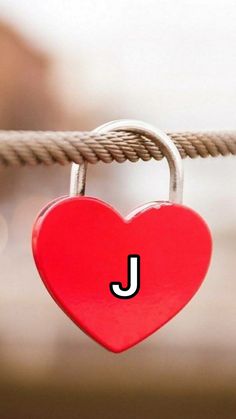 a red heart hanging from a rope with the letter j on it's side