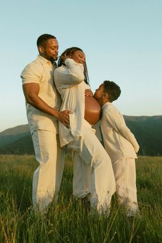 a man and two women are standing in the grass with their arms around each other