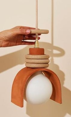 a hand holding an object made out of rocks and wood with a white ball on top