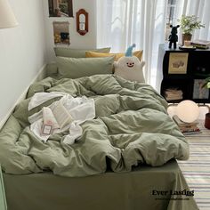 an unmade bed in a bedroom with green sheets and pillows on top of it