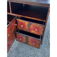 an old dresser has been painted red and yellow with rusted paint on the drawers