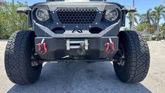 the front end of a gray four - doored vehicle with large tires and lights