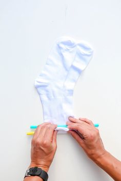 someone is holding up a pair of white socks with blue and yellow toothbrushes