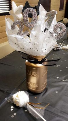 a table topped with a jar filled with white and black paper mache flowers next to a pair of scissors