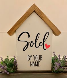 a sign that says sold by your name on the side of a house with flowers