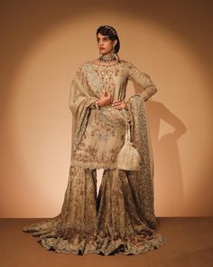 In a delicate shade of light coffee, this organza shirt features full sleeves and a boat neckline, exuding understated elegance. Paired with an organza farshi gharara adorned with intricate borders, this ensemble is perfect for those seeking the latest trends in wedding gharara fashion, offering a blend of tradition and modernity.In an ode to timeless elegance, this regal bridal ensemble emerges, bathed in the delicate hue of light coffee. Adorned with meticulous artistry, the ensemble is a cele Kameez Style, Bridal Gharara, Wedding Dresses Pakistani, Pakistani Bridal Dress, Bridal Dupatta, Organza Shirt, Wedding Clothes, Traditional Bride, Pakistani Bridal Dresses