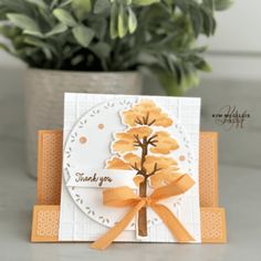 an orange and white card with a tree on the front, thank you written in gold