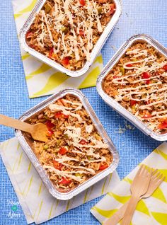 three pans filled with food sitting on top of a blue table covered in napkins