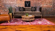 a living room with brick walls and wooden flooring, two couches and a coffee table