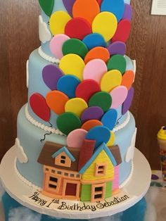 a birthday cake decorated with balloons and houses