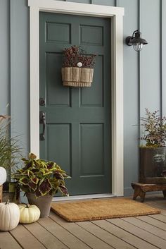 the front porch is decorated for fall with pumpkins and potted plants on the floor