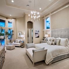 a large bedroom with white furniture and chandelier