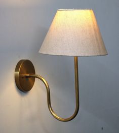 a wall light with a white shade on it's side and a lamp plugged into the wall