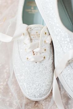 a pair of white tennis shoes with bows on the laces and sequins