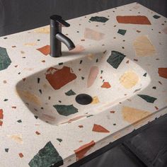 a bathroom sink with multicolored tiles on the counter top and black faucet