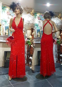 two mannequins wearing red dresses in front of a fireplace