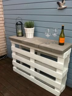 an outdoor bar made out of wooden pallets with wine glasses and bottles on top