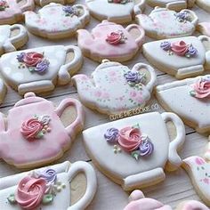 decorated cookies with teapots and roses are on the table for guests to eat