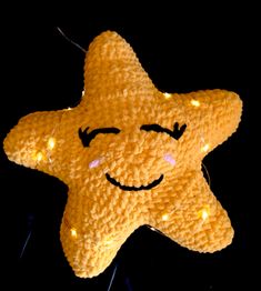 a yellow stuffed star hanging from a string with lights around it's eyes and smiling face