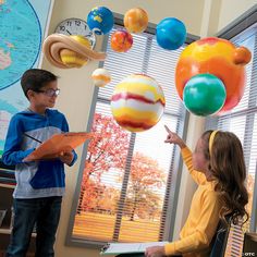 two children are playing with colorful balls in an office setting, while another child is pointing at them