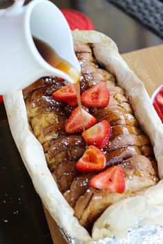 someone is pouring syrup on some bread with strawberries