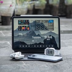 an open laptop computer sitting on top of a tiled floor next to ear buds and headphones