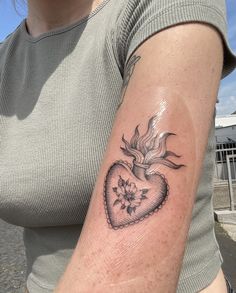 a woman's arm with a heart and flower tattoo on the left side of her arm