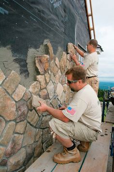 two men working on a stone wall