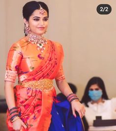 a woman in an orange and blue sari walks down the runway with her hand on her hip