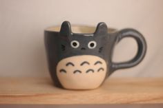 a black and white coffee cup with a totoro face on it