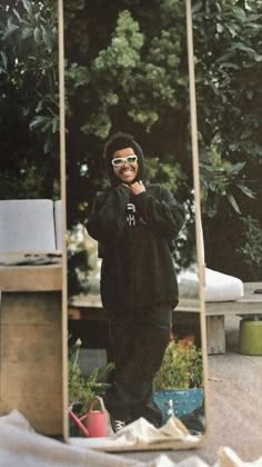 a young man wearing sunglasses is taking a selfie in front of an old mirror