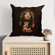 a pillow with a painting of jesus on it and a vase in front of it