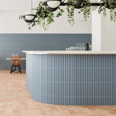 a bar with plants hanging from it's ceiling in a room that has blue tiles on the walls