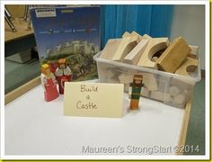 some wooden toys are on a table with a sign that says build a castle in front of them